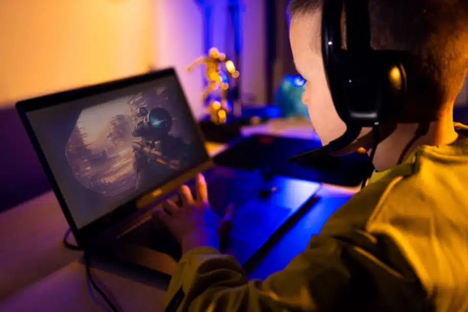Child playing video game on laptop with headset