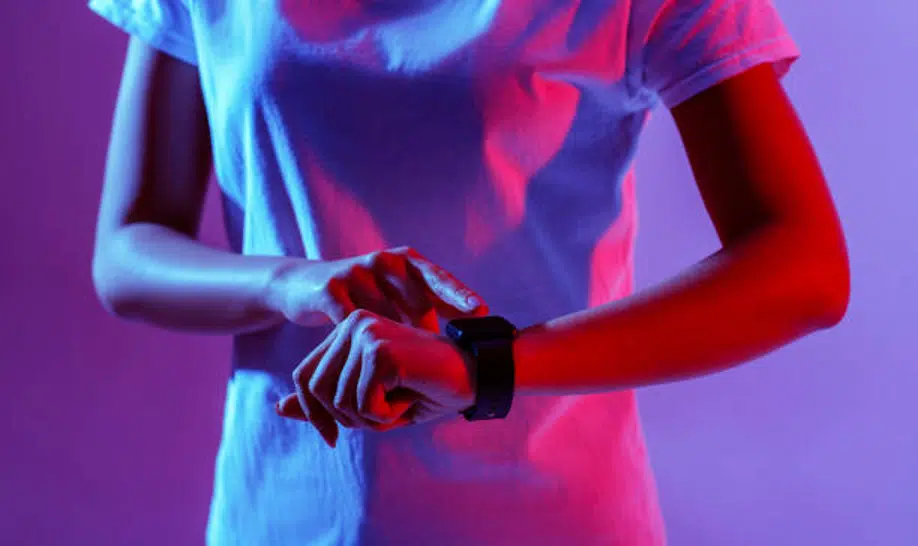Person using smartwatch under colorful lighting